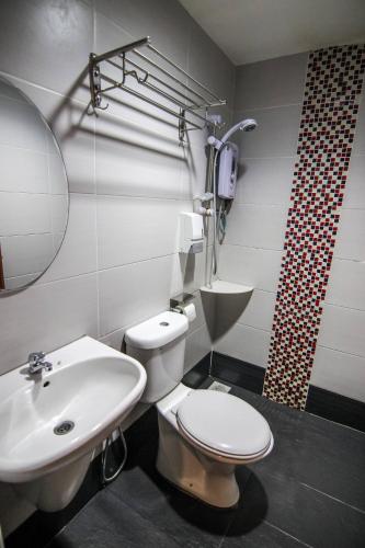 y baño con aseo y lavamanos. en Rose Cottage Hotel Taman Nusa Cemerlang, en Gelang Patah