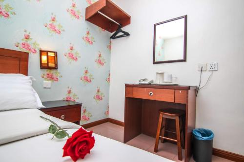 a bedroom with a bed and a vanity with a mirror at Rose Cottage Hotel Taman Daya in Johor Bahru