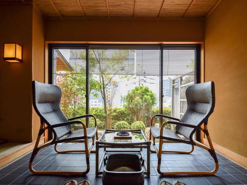 松山的住宿－道後溫泉大和屋別荘，窗户客房内的两把椅子和一张桌子