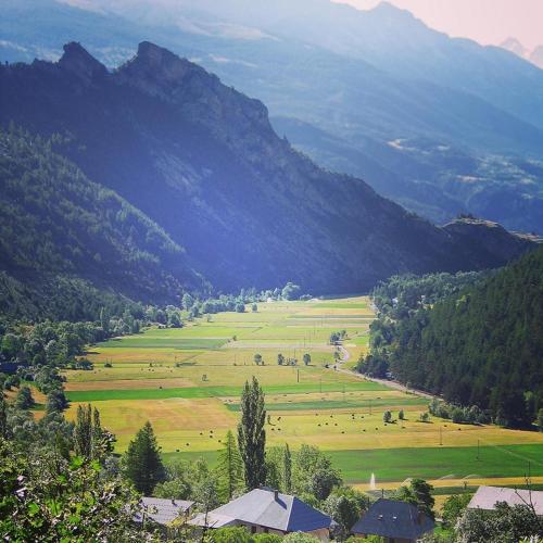 a view of a large field with mountains in the background at Le balcon fleuri in Freissinieres