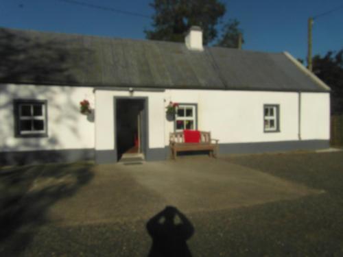 a white house with a red chair in front of it at Country Cottage in Portarlington