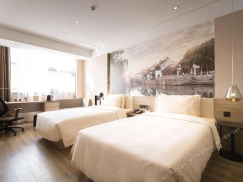 two beds in a hotel room with a painting on the wall at Atour Hotel Suzhou Industrial Park Qingjian Lake Branch in Suzhou