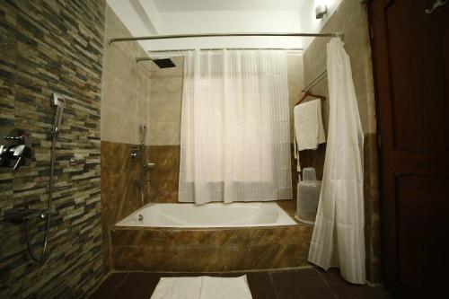 a bathroom with a tub and a shower with a shower curtain at Yangthang Heritage in Gangtok