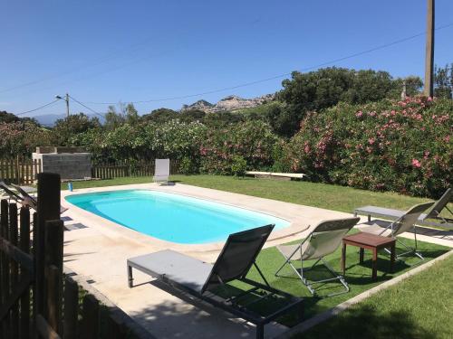 a swimming pool with two lawn chairs and a table and two chairs at Agréable Location au coeur du vignoble DOMINICI THERESE in Patrimonio
