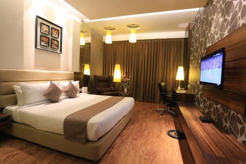 ein Hotelzimmer mit einem Bett und einem Flachbild-TV in der Unterkunft The Vivaan Hotel & Resorts Karnal in Karnal