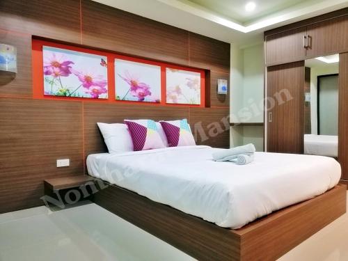 a bedroom with a large bed with white sheets at Nontharat Mansion in Nonthaburi