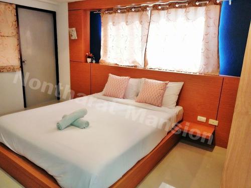 a bedroom with a bed with a stuffed animal on it at Nontharat Mansion in Nonthaburi