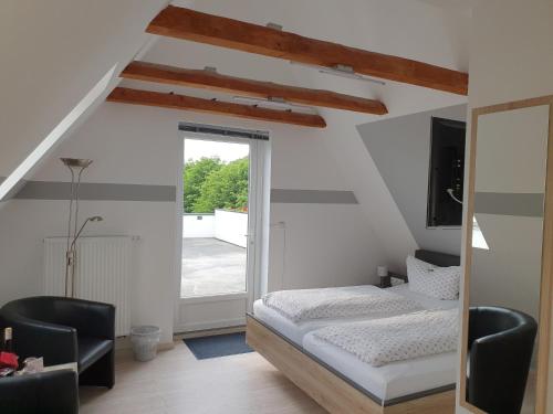 a bedroom with a bed and two chairs and a window at Pension Marktblick in Friedrichstadt