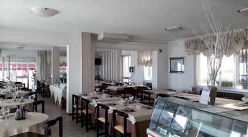 una sala da pranzo con tavoli, sedie e finestre di Hotel Oasi Ristorante Pizzeria a Fano