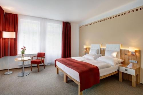 a bedroom with a large bed and a table and chair at Hotel Astoria in Jáchymov