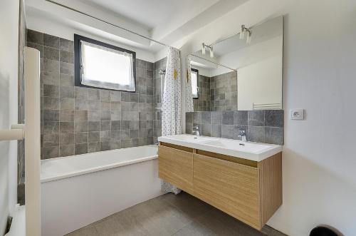 a bathroom with a sink and a tub and a mirror at Maison du Prignon in Saint-Marc-Jaumegarde