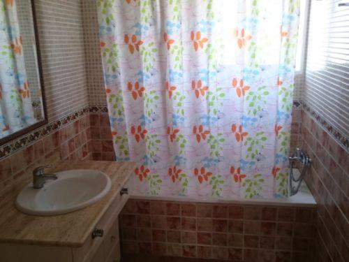 a bathroom with a sink and a shower curtain at Ático Playa in Cartagena