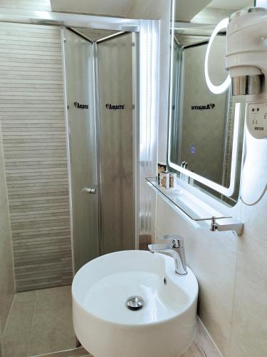 a bathroom with a white sink and a shower at Amarru Apartments in Piran