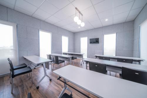 an empty classroom with tables and chairs and windows at All Nite & Day Kebon Jeruk in Jakarta