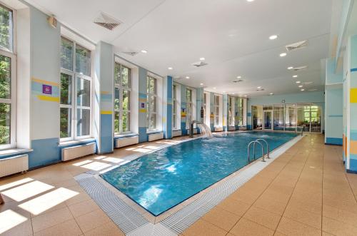 a swimming pool in a building with windows at Istra Holiday Hotel in Trusovo