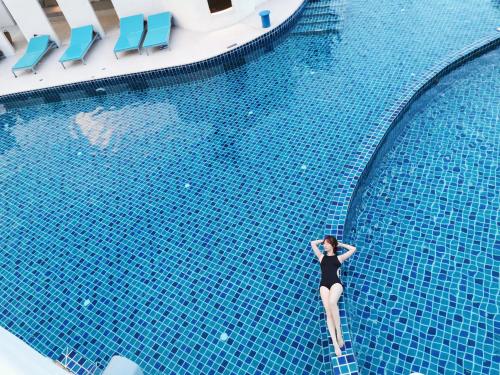 Eine Frau in einem schwarzen Kleid steht im Pool in der Unterkunft The Oia Pai Resort in Pai