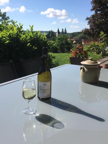 - une bouteille de vin assise sur une table avec un verre dans l'établissement La Chambre des Buissonnats, à Martailly-lès-Brancion