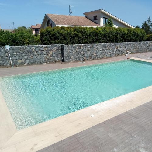 a swimming pool in front of a stone wall at B&B nna'vigna in Viagrande
