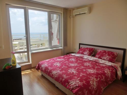 Schlafzimmer mit einem roten Bett und einem großen Fenster in der Unterkunft 2 bedroom Imperial apartment with panoramic sea views, Sveti Vlas in Sweti Wlas