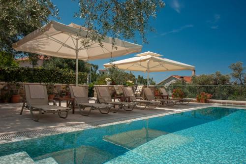 a group of chairs and umbrellas next to a pool at Villa Stevan in Sveti Stefan