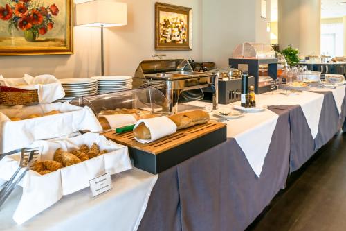a buffet line with tables filled with bread and pastries at Grand Hotel Mattei in Ravenna