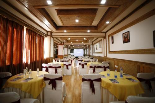 a room with tables and chairs with yellow and white tablecloths at Yangthang Heritage in Gangtok