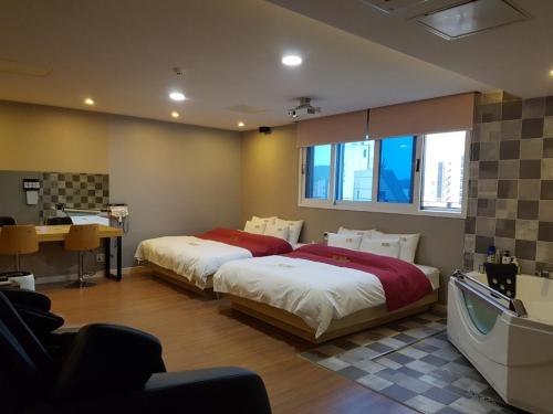 a bedroom with two beds and a desk in it at No.1 New Yorker Hotel in Jinju