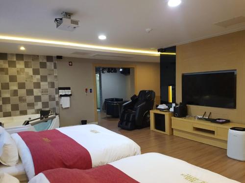a hotel room with a bed and a flat screen tv at No.1 New Yorker Hotel in Jinju