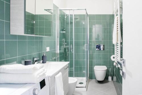 e bagno piastrellato verde con servizi igienici e doccia. di Oasi Casa Vacanze a Loano
