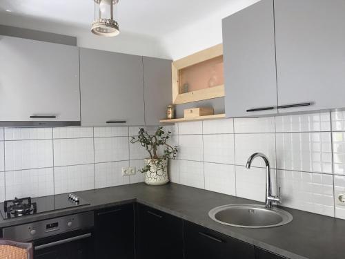 a kitchen with a sink and white tiled walls at P. Stradiņa iela 17 Апартаменты in Ventspils