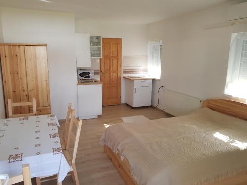 Cette chambre comprend un lit, une table et une cuisine. dans l'établissement Pagrepe apartman, à Balatonvilágos