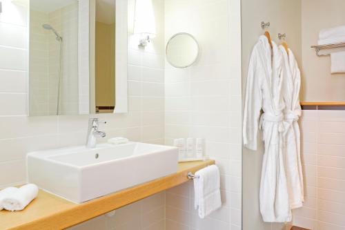 a white bathroom with a sink and a mirror at Radisson Blu Hotel Toulouse Airport in Blagnac