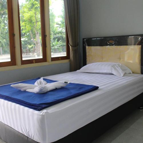 a bed with a towel on it with two windows at Pondok Wisata dan Restoran Elim in Waingapu