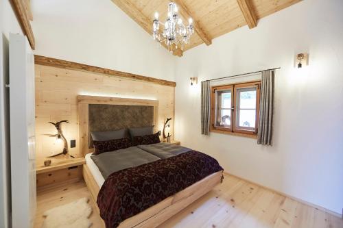 a bedroom with a large bed and a chandelier at Dreisessel-Chalets im bayerischen Wald in Haidmühle