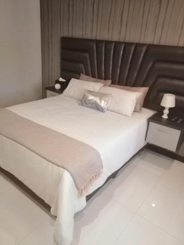 1 dormitorio con 1 cama blanca grande y cabecero de madera en Erasmia Palms Boutique Hotel & Spa en Centurion