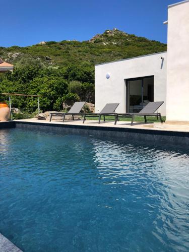 - une piscine avec deux bancs en face d'une maison dans l'établissement Villa A Luna, à Pietracorbara