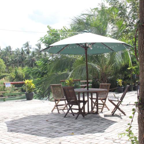 a table and chairs under an umbrella on a patio at Pondok Wisata dan Restoran Elim in Waingapu