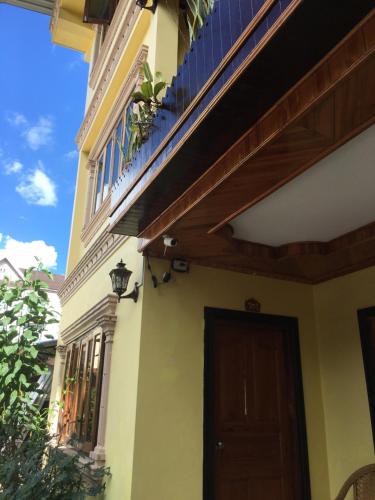 Casa con puerta de madera y balcón en Thoulasith Guesthouse, en Luang Namtha
