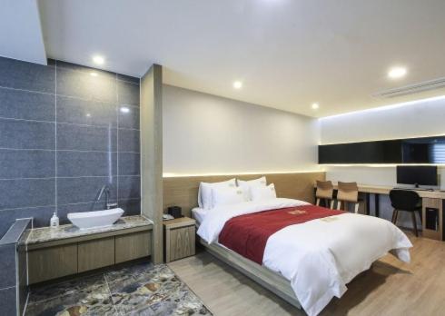 a bedroom with a bed and a bathroom with a sink at No.1 New Yorker Hotel in Jinju