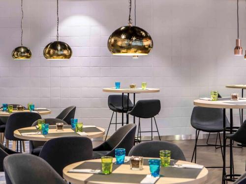 a dining room with tables and chairs and lights at Novotel Szczecin Centrum in Szczecin