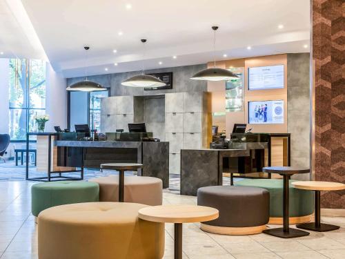 a lobby with tables and stools in a building at Novotel Szczecin Centrum in Szczecin