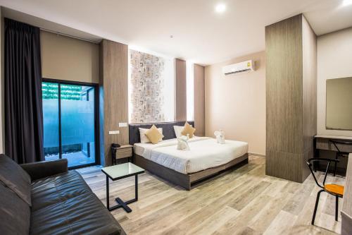 a hotel room with a bed and a couch at Tara Park Resotel in Ban Talat Rangsit