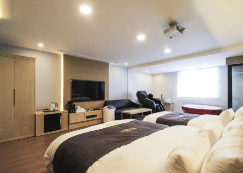 a hotel room with two beds and a flat screen tv at No.1 New Yorker Hotel in Jinju
