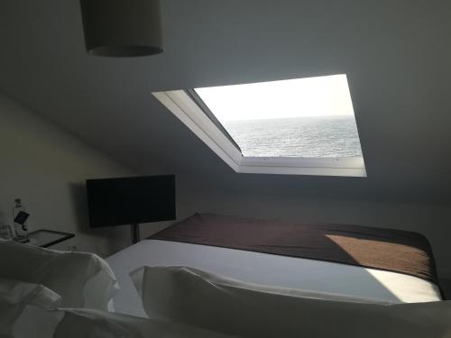 a bedroom with a bed and a window with the ocean at Promar - Eco Beach & Spa Hotel in Maceira