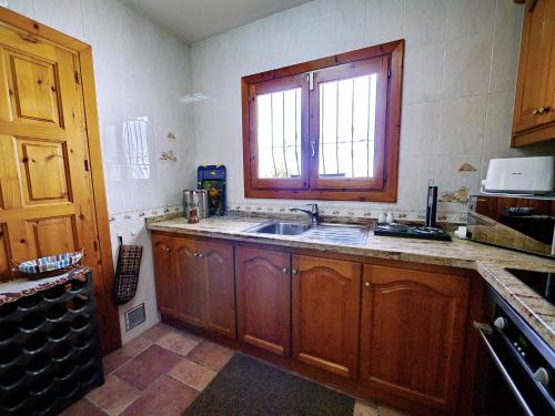 a kitchen with wooden cabinets and a sink and a window at Villa Sophie 4 - by Holiday Rentals Villamar in Benitachell