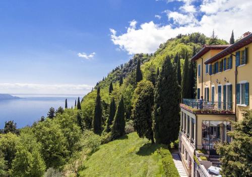 a house on a hill with a view of the water at Boutique Hotel Villa Sostaga in Gargnano
