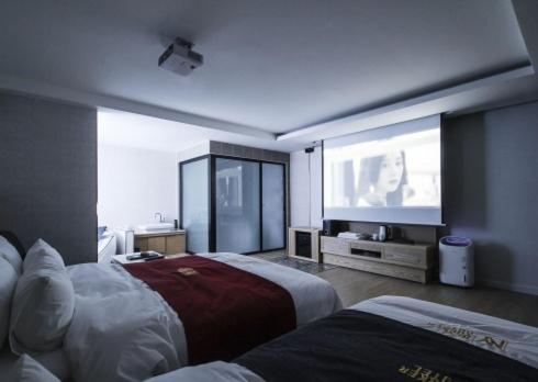 a hotel room with two beds and a flat screen tv at No.1 New Yorker Hotel in Jinju