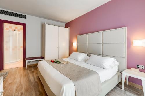 a bedroom with a large white bed with purple walls at Best Western Hotel Imperiale in Nova Siri Marina