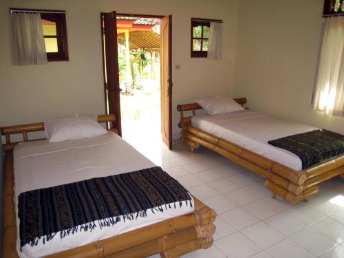 two beds sitting in a room with a door at Secret Garden Bungalows in Nusa Lembongan
