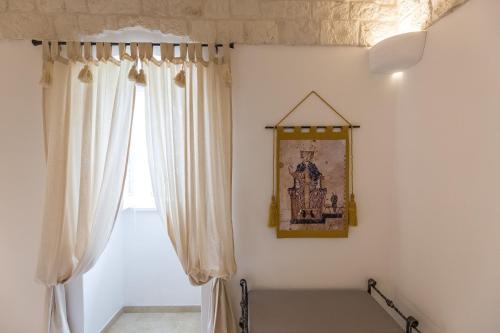 a room with white curtains and a picture on the wall at Dimora San Quirico - bed e breakfast - Cisternino in Cisternino